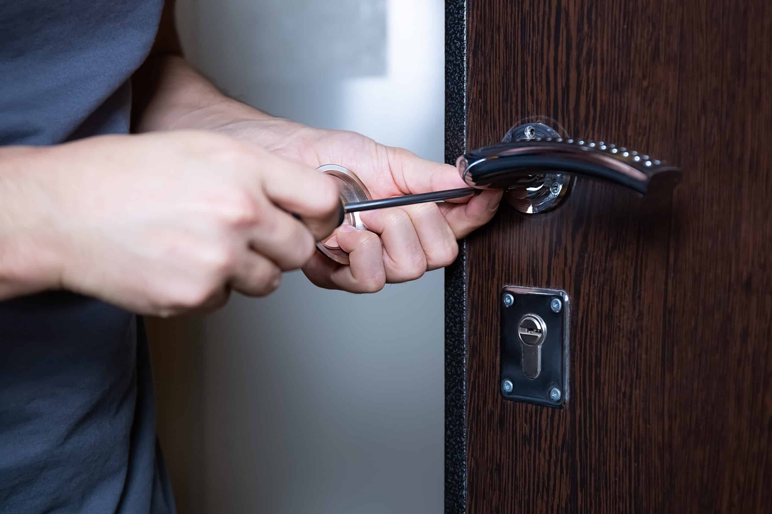 Serrurier remplaçant une serrure de porte après perte de clés. Protection contre le vol, amélioration de la sécurité. Gros plan sur les mains d'un réparateur ou d'un ouvrier changeant ou réparant une serrure de porte.